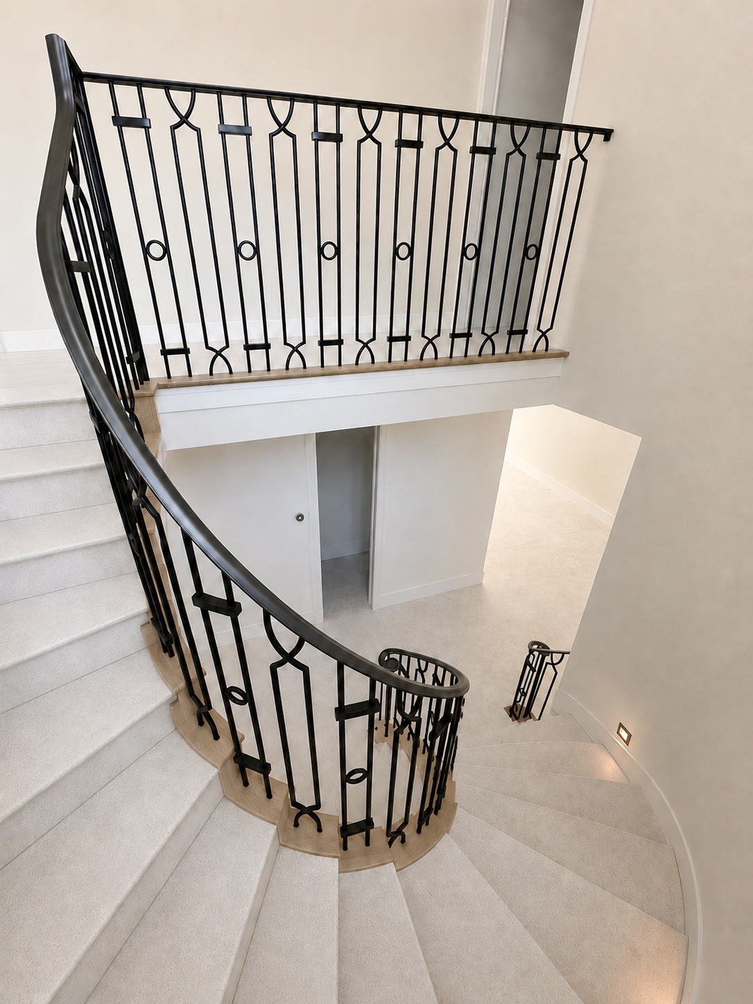 Interior curved stair railing with decorative iron panels