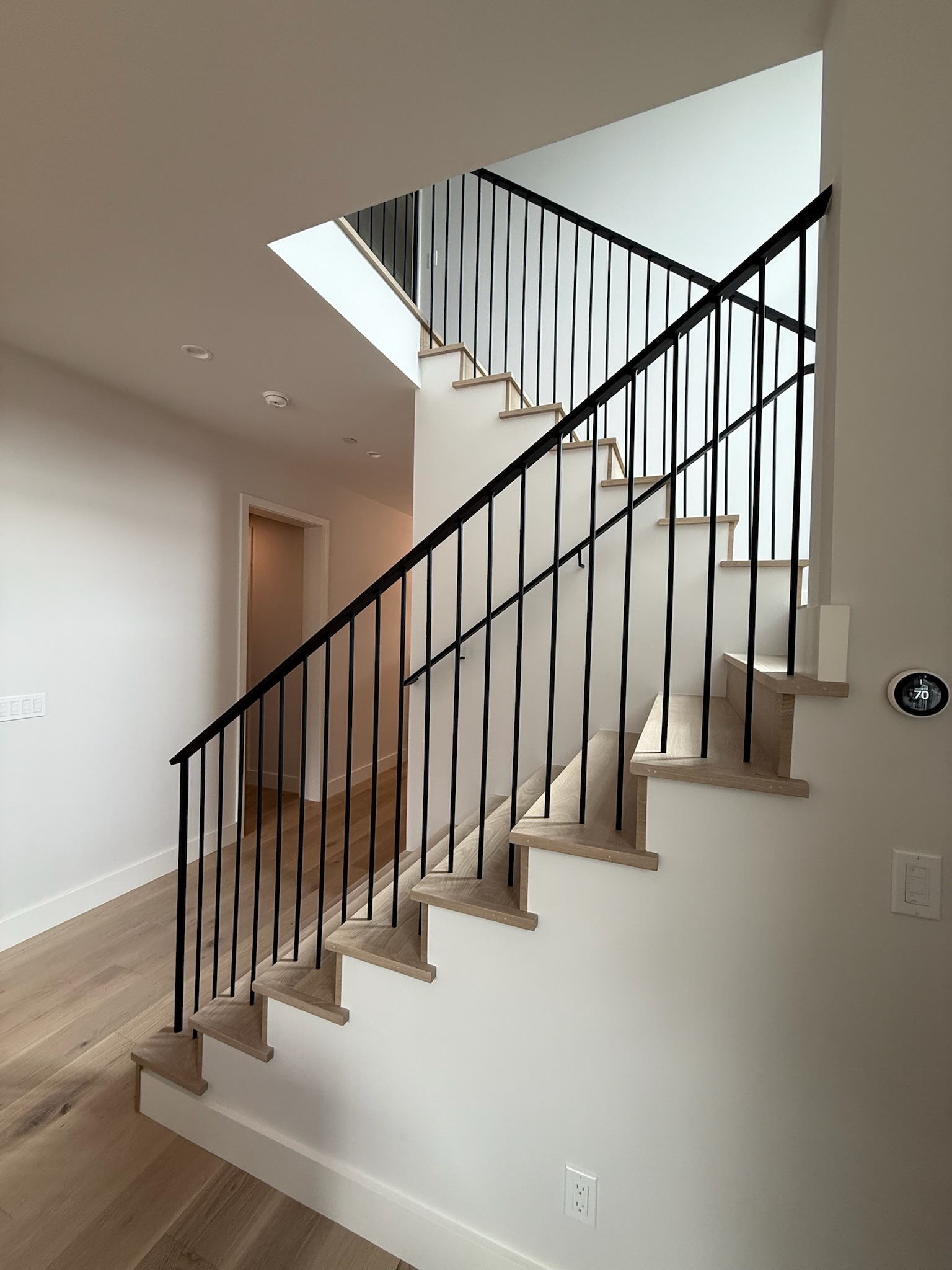 Modern black vertical stair railing with light wood steps