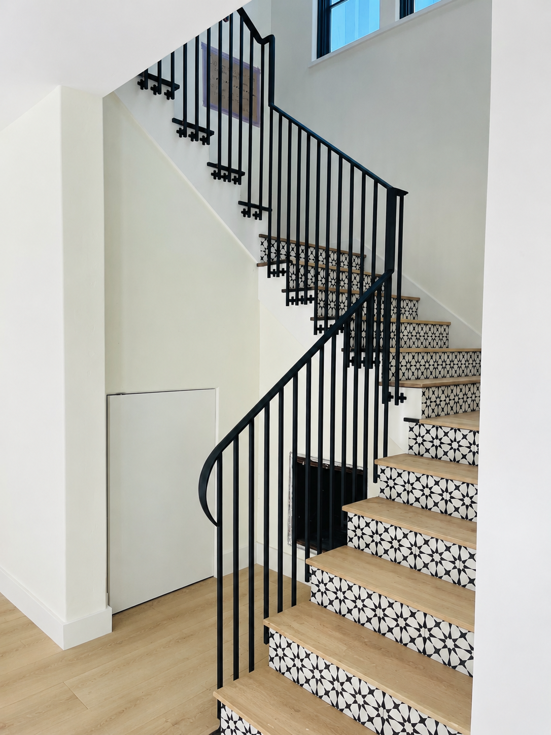 Black stair railing with patterned stair risers and wood treads