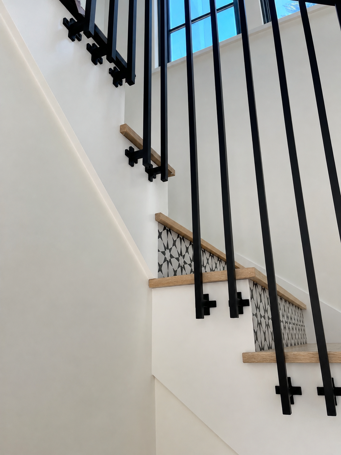 Close detail of black stair railing above patterned stair risers