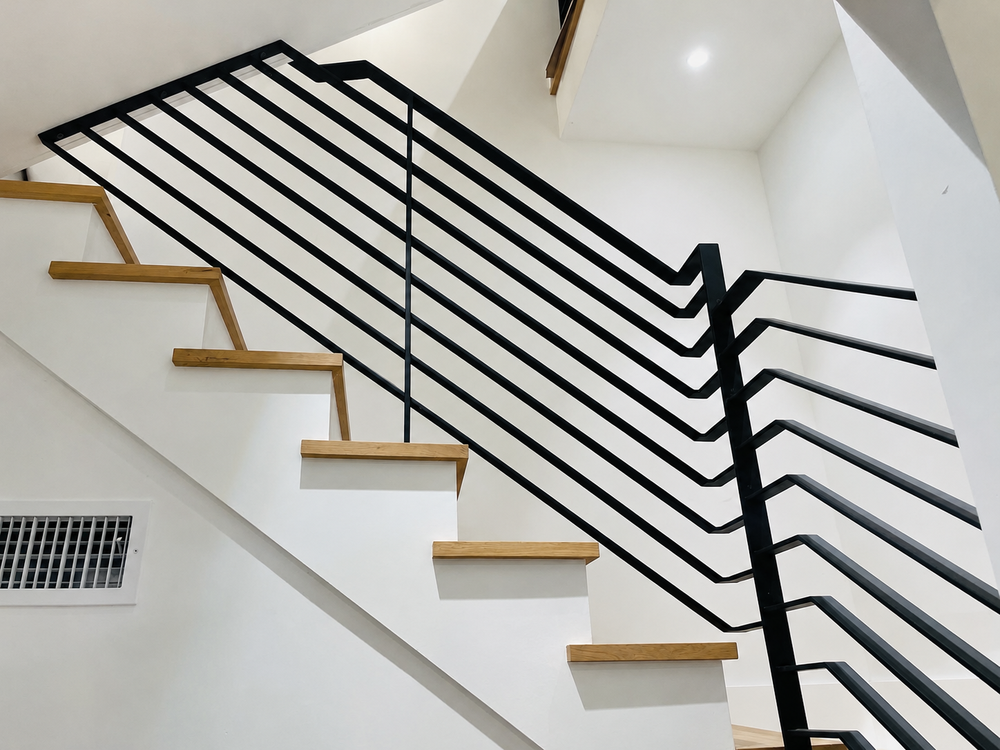 Close view of black horizontal stair railing and wood steps