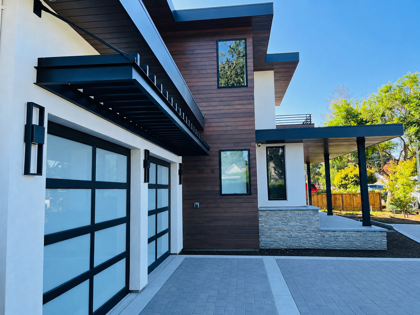 Black metal trellis over modern garage doors and wood facade