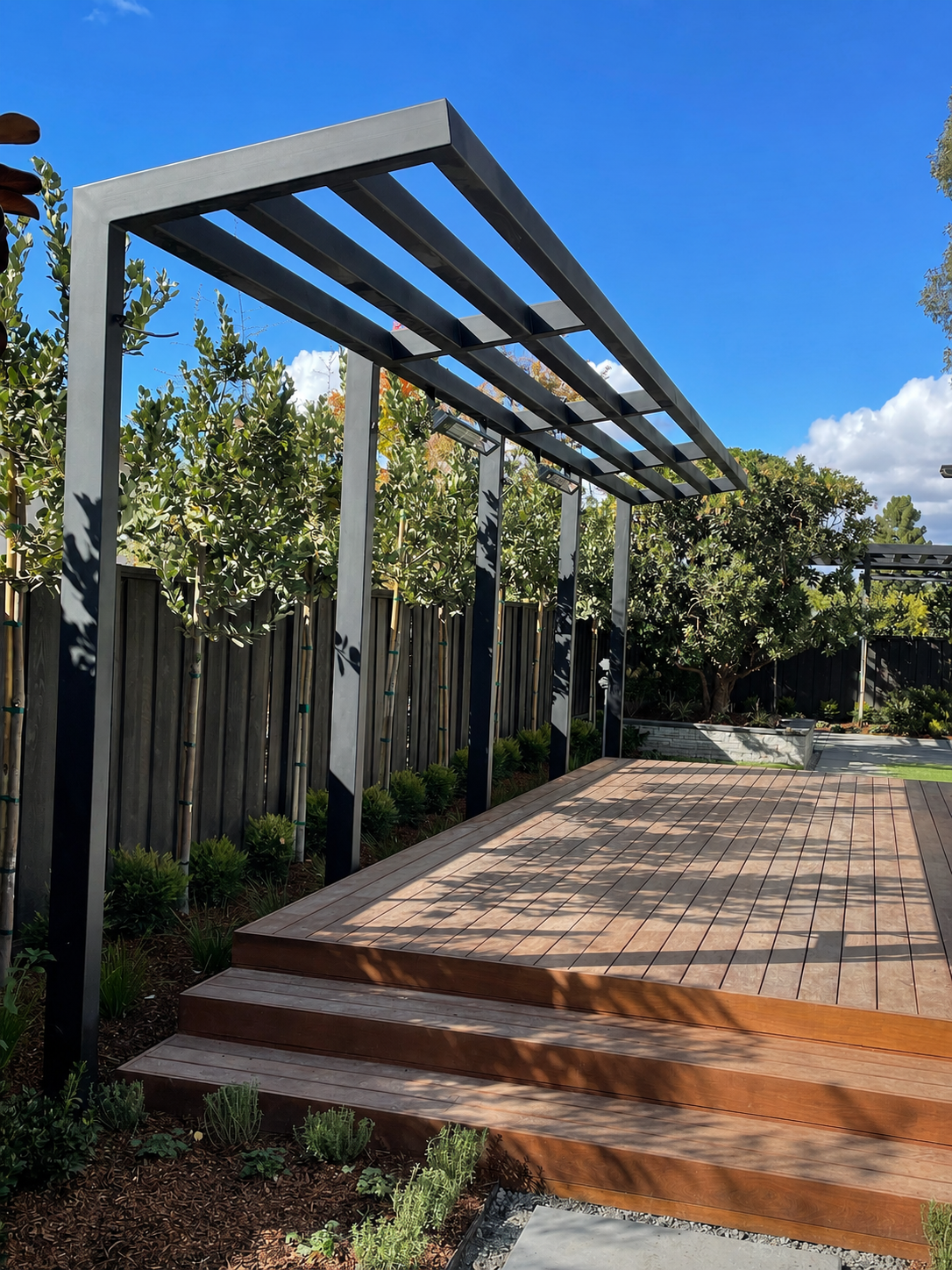 Black metal trellis over wood deck and garden