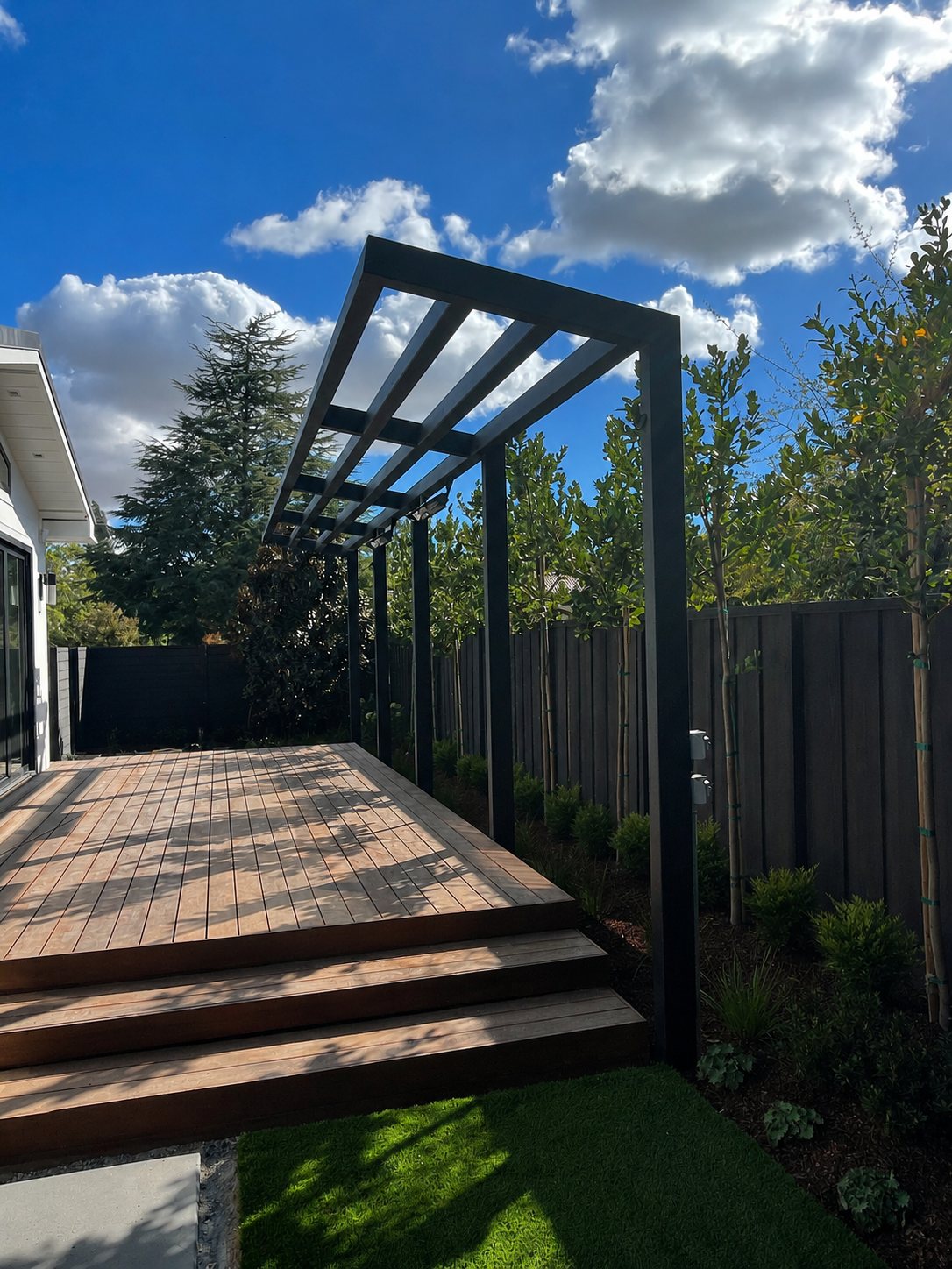 Black metal trellis over deck beneath blue sky