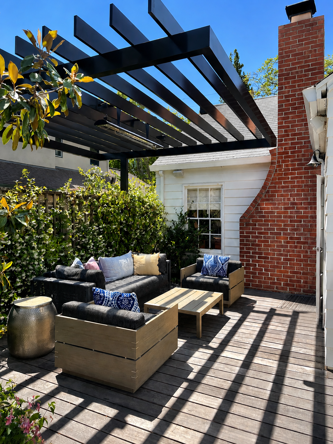 Black metal trellis over outdoor lounge and brick fireplace