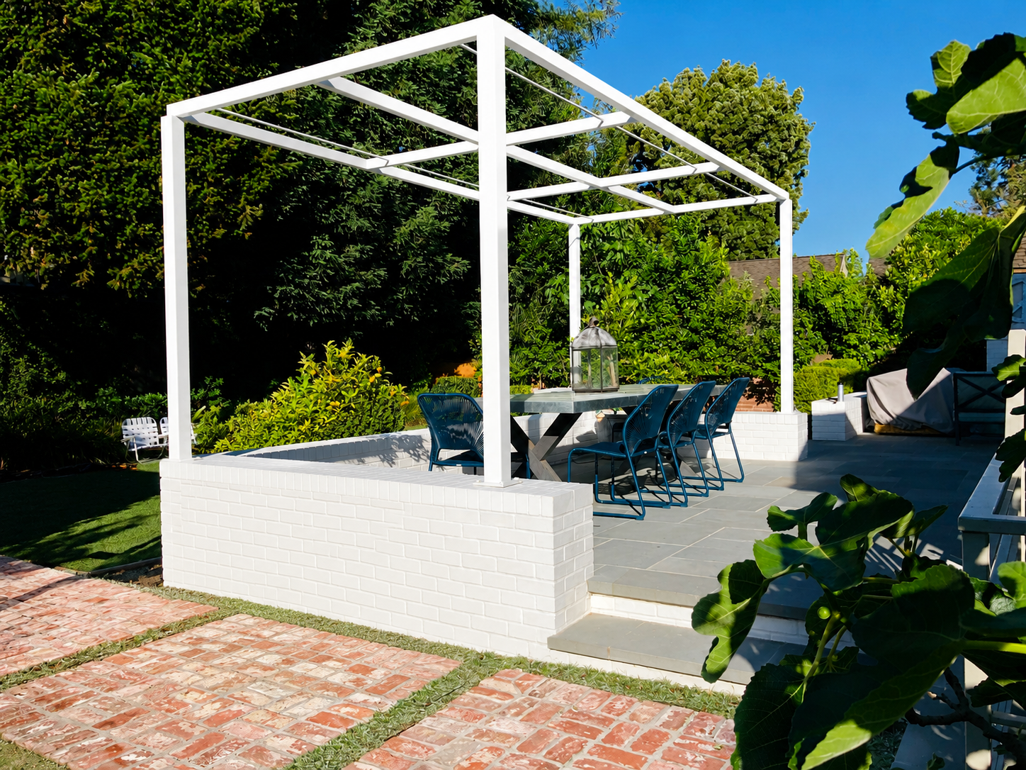 White patio trellis frame above brick path and garden plants