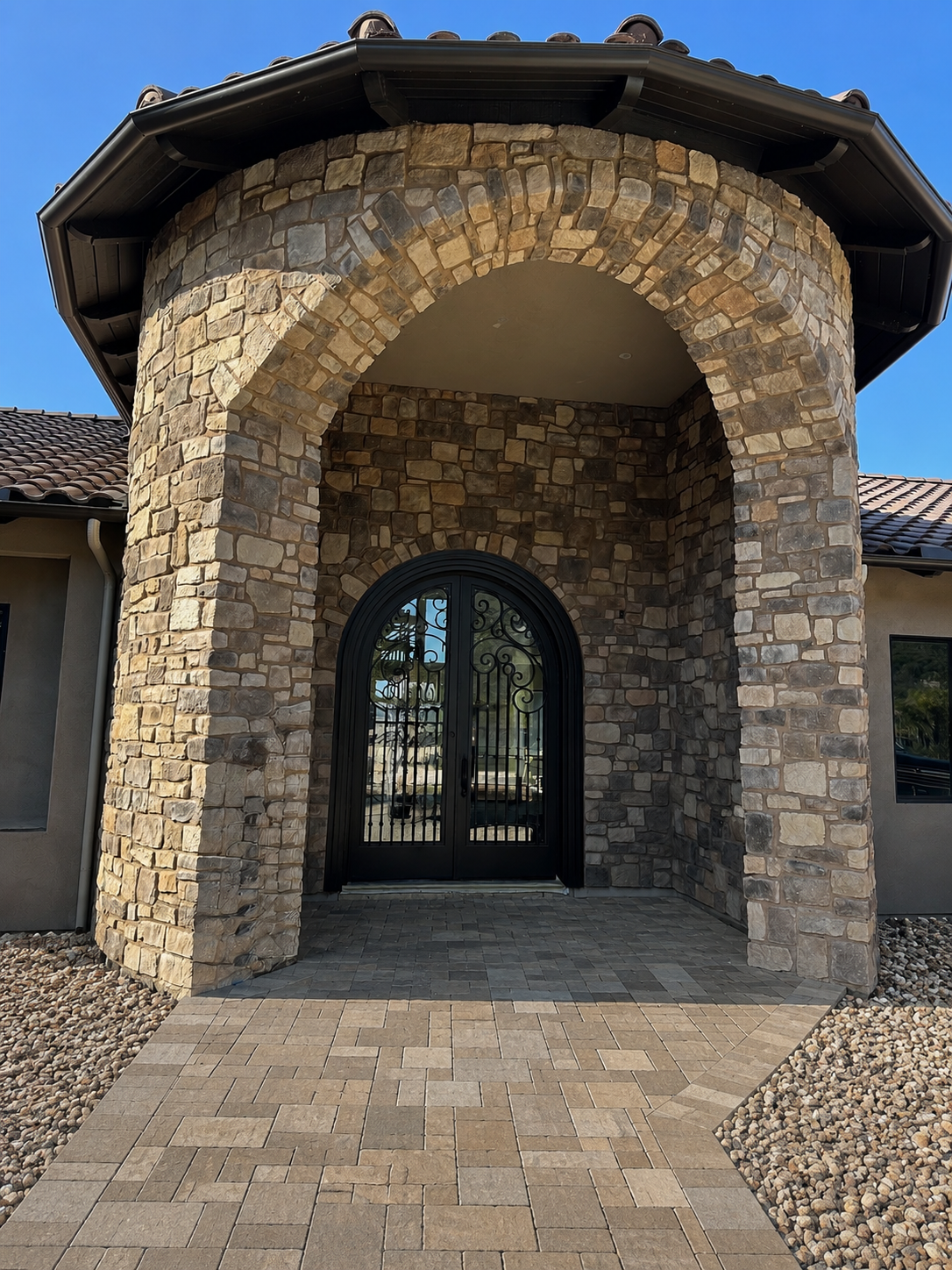 Arched stone home entry with ornamental iron doors